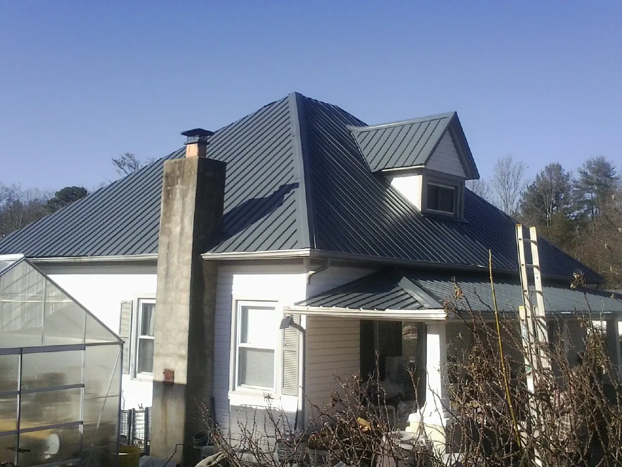 Dark blue standing seam metal roof on a white farmhouse with dormer — Slate & Tile Roof Repair by Roofing Brothers in Gibbonsville