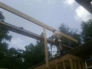 Carpenter setting a ridge beam over a new addition frame — Ice Dam Removal by Roofing Brothers in Gibbonsville