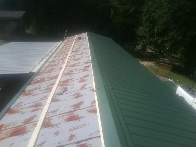 Old rusted panels beside newly installed green metal roofing — Wind Damage Roof Repair by Roofing Brothers in Gibbonsville