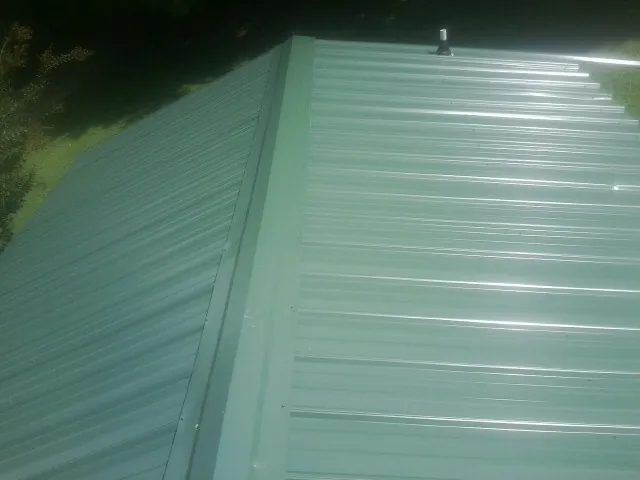 New green metal panels meeting at the ridge of a roof — Flat Roof Repair work by our crew in Gibbonsville