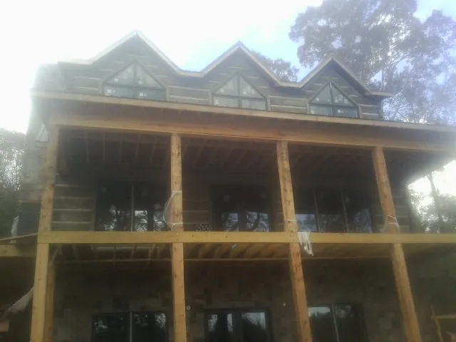 Dormers and porch framing on a large log home under construction — Roof Coating work by our crew in Gibbonsville
