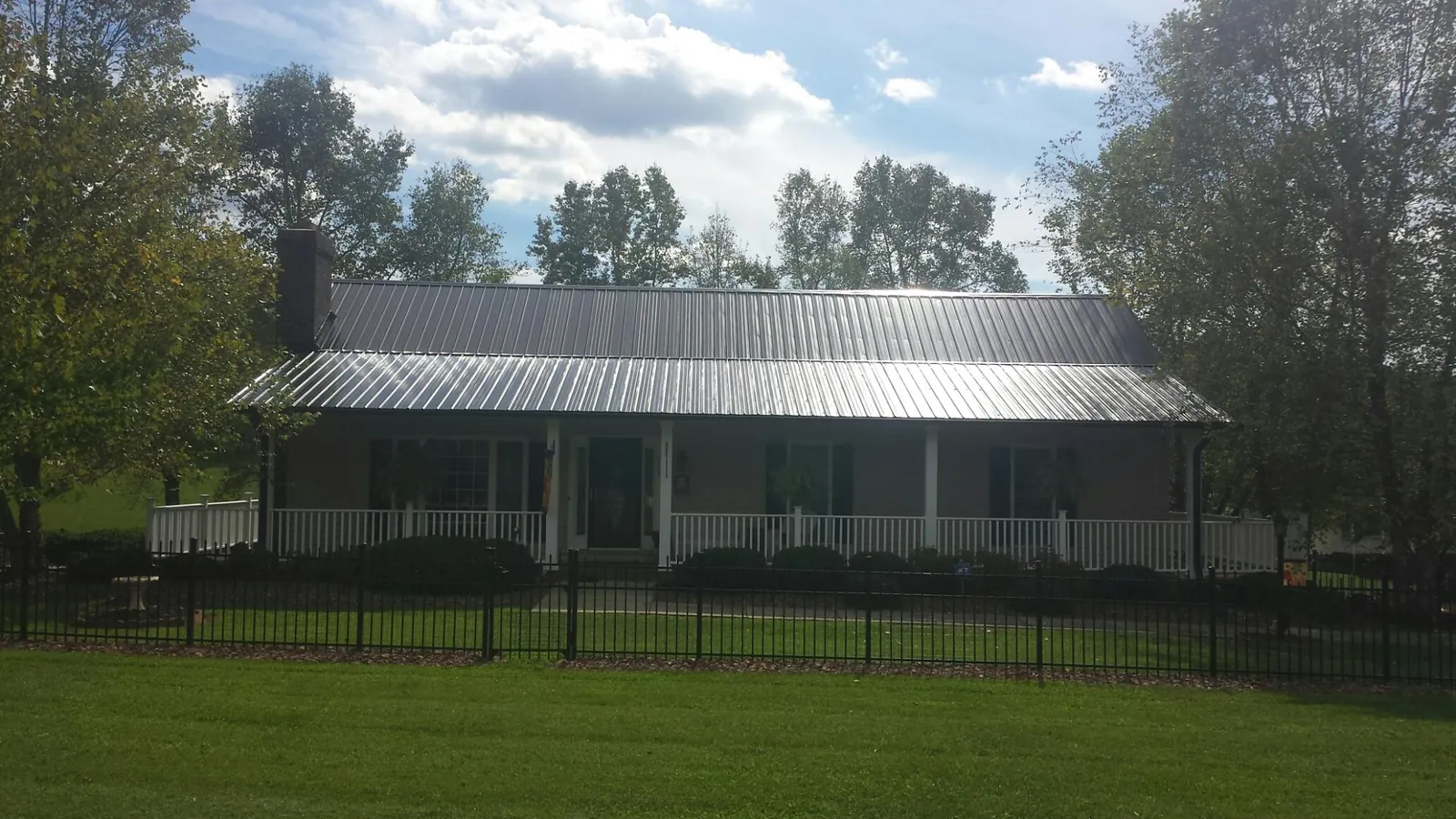 Gray metal roof on a brick ranch with a full width front porch — Gutter Guard Installation work by our crew in Gibbonsville