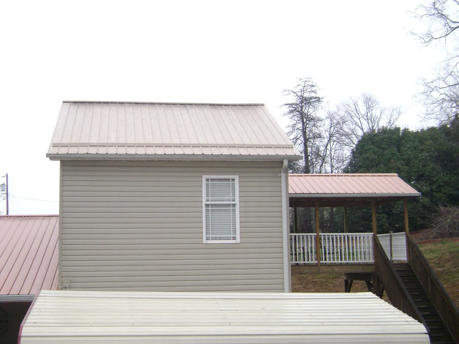 Tan metal roofs on a two story addition and attached porch, from a Roof Replacement job in Gibbonsville