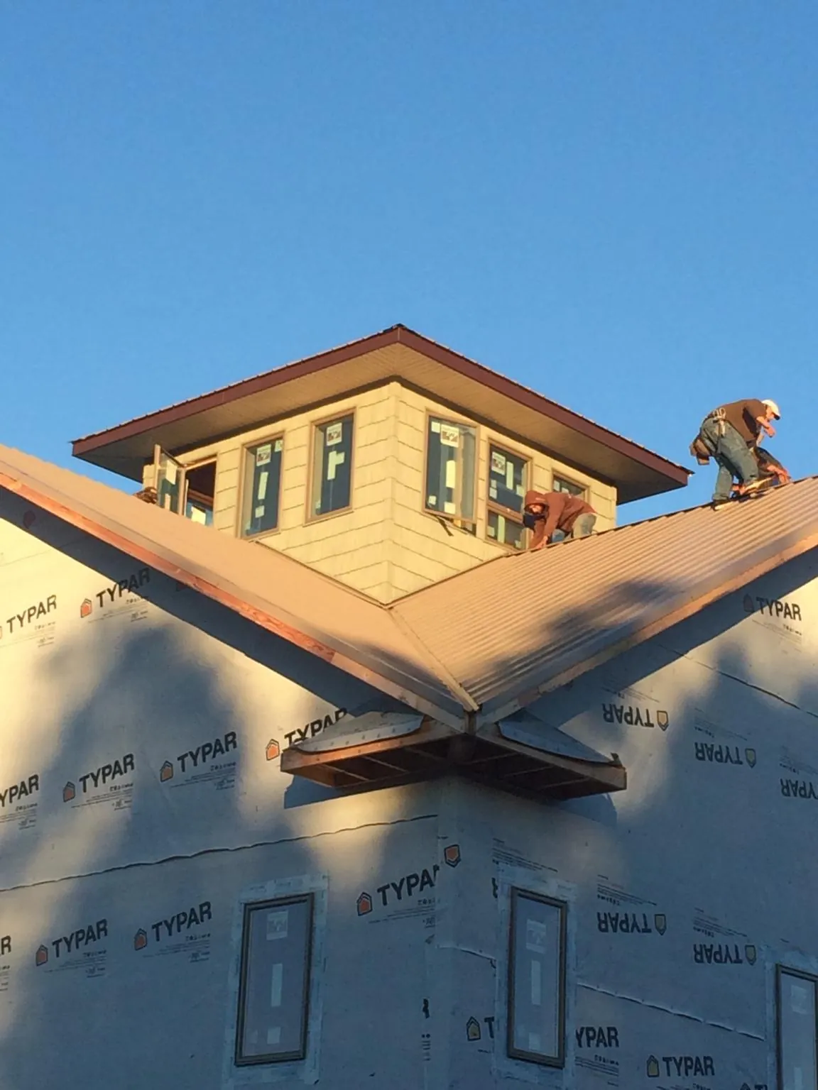 Roofers working around a rooftop cupola on a new metal roof at sunset — Roof Waterproofing in Gibbonsville by Roofing Brothers